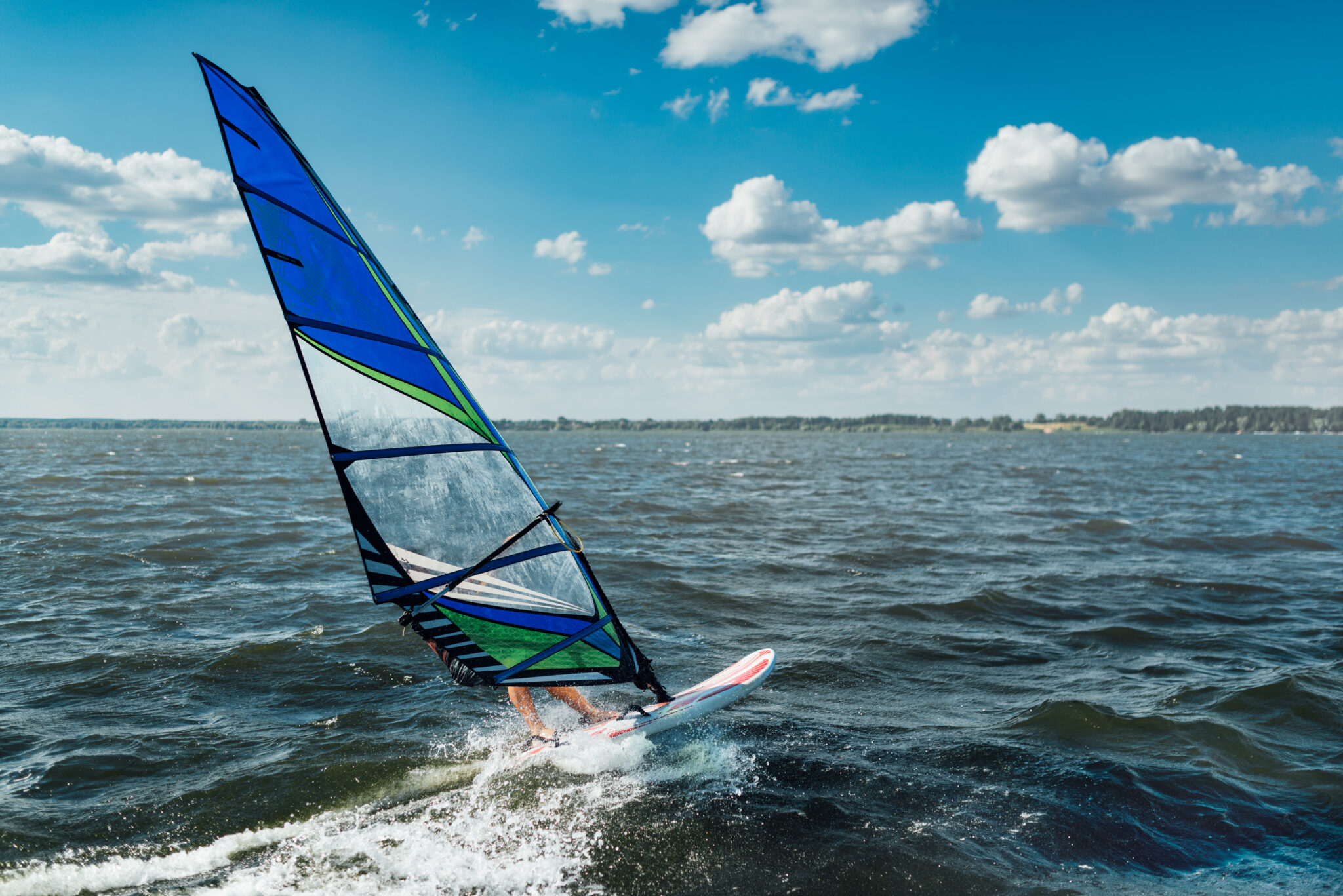 the man athlete rides the windsurf over the waves on the lake